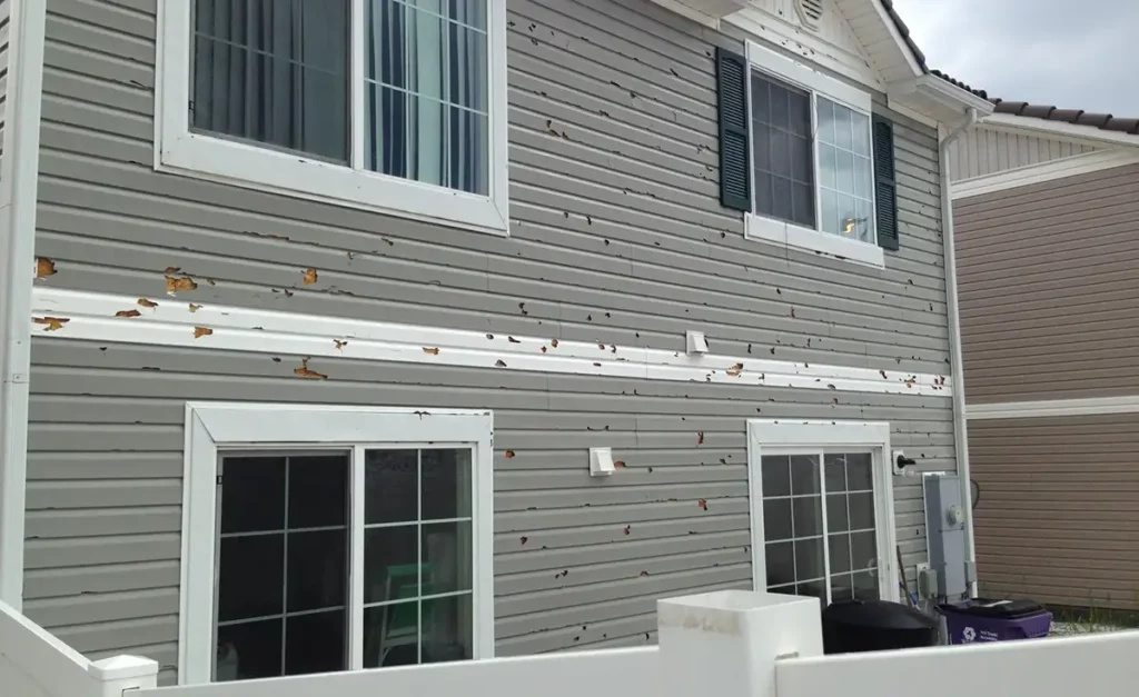 Siding of a home damaged after high winds and hail.